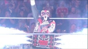 Penta raises his fist in the ring behind his custom Dinero en el Banco Money in the Bank briefcase on WWE Raw