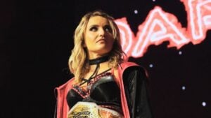 Xia Brookside stands on the TNA stage wearing the Knockouts World Championship and a red entrance jacket