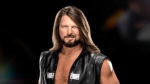 AJ Styles in a black leather vest posing against a dark background