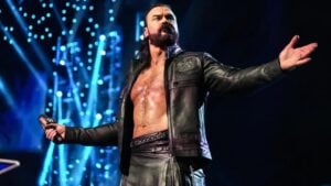 Drew McIntyre holds a microphone with his arms outstretched on a WWE stage