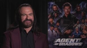 Drew McIntyre smiles during an interview in front of an Agent of Shadows poster
